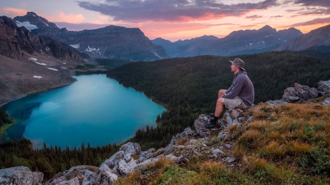 Wanderer oberhalb eines Bergsees bei Abendlicht
