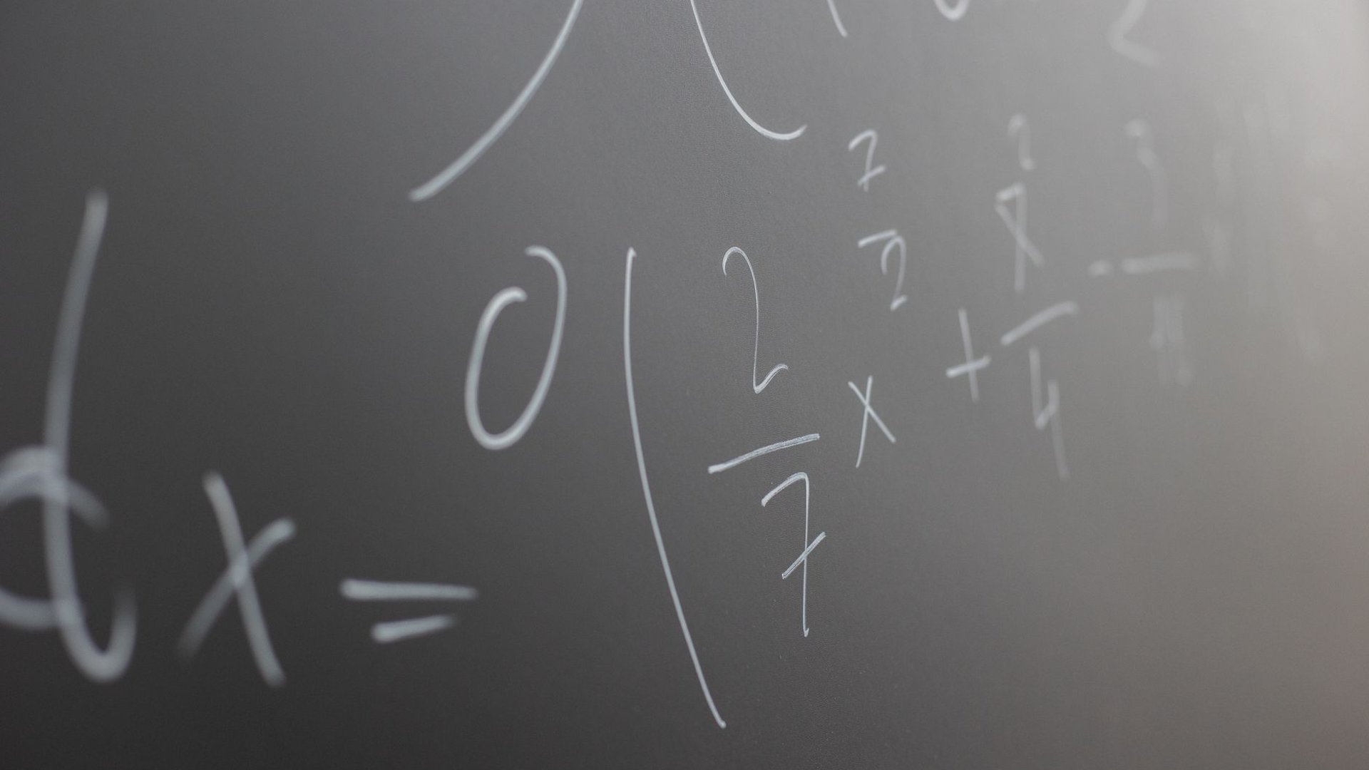 Tafel mit handgeschriebenen mathematischen Formeln und Brüchen – Motiv für Mathe Witze