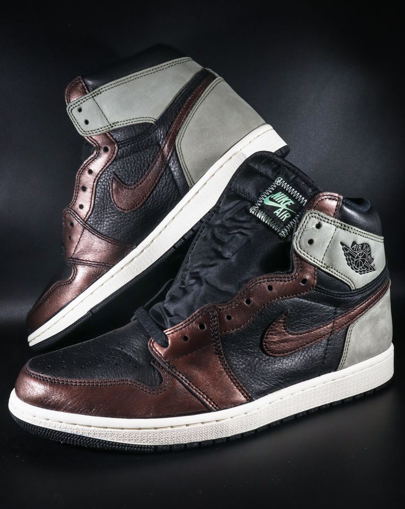 Ein Paar Nike Air Jordan 1 High Sneaker in Schwarz mit bronzefarbenen Metallic-Akzenten und grauem Wildleder