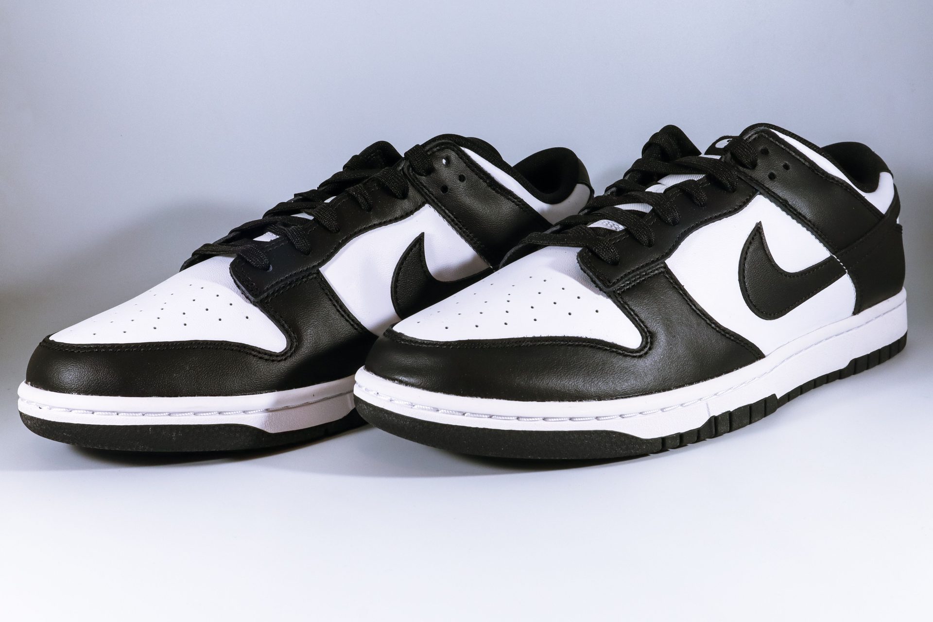 Zwei Nike Dunk Low Sneaker im klassischen Schwarz-Weiss-Farbblockdesign, frontal fotografiert
