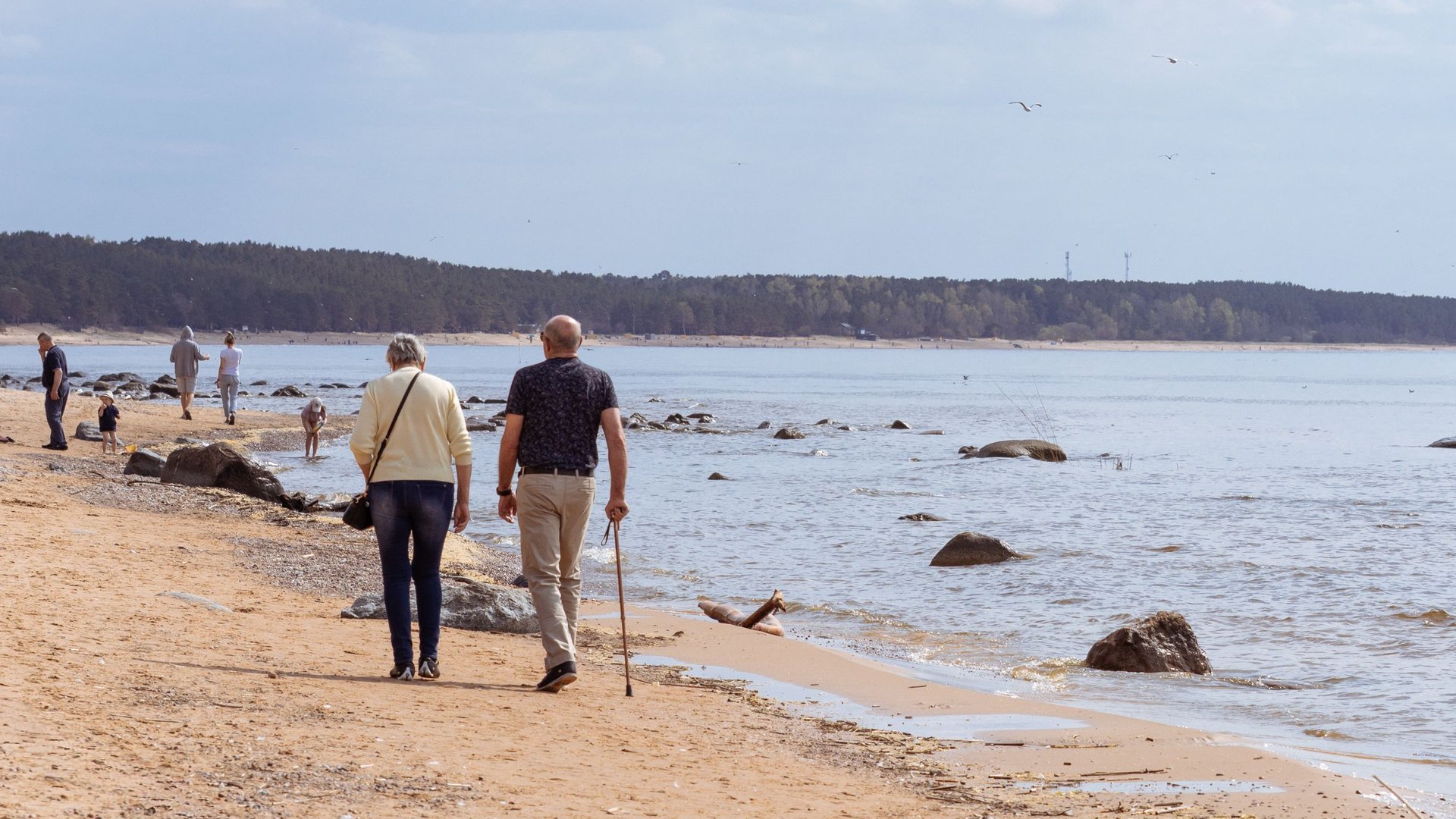 Älteres Paar spaziert an einem ruhigen Ostseestrand entlang (Symbolbild)