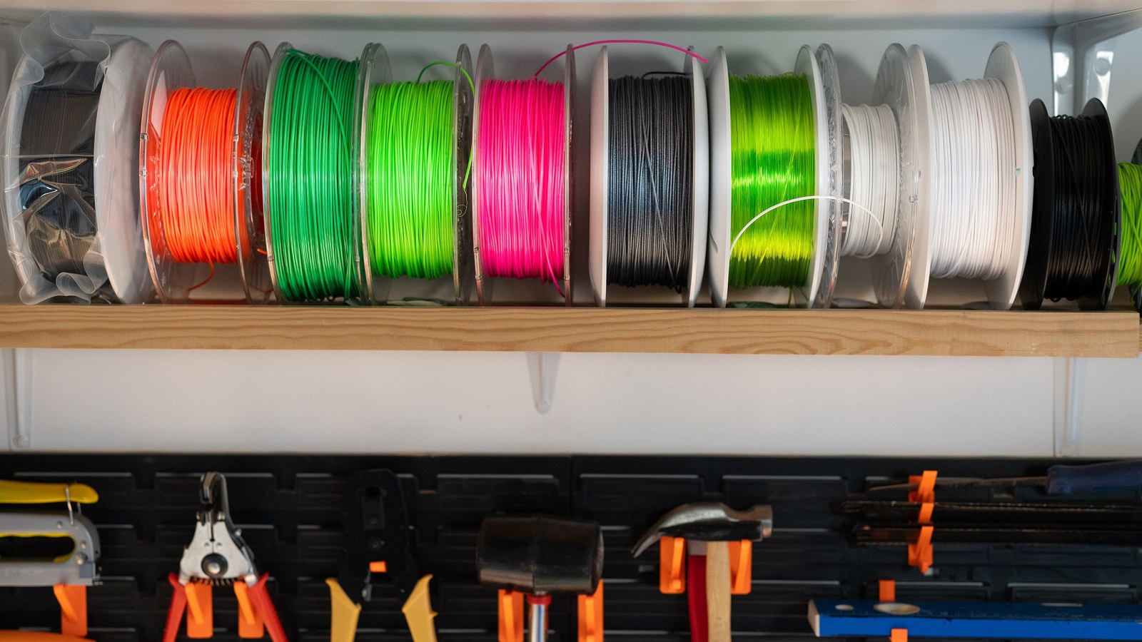 Verschiedenfarbige 3D-Druck-Filamentspulen in einem Werkstattregal