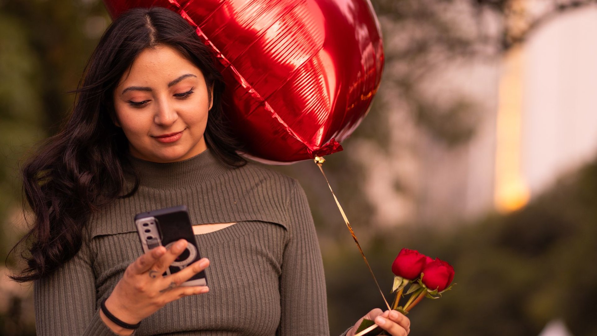Frau mit rotem Luftballon liest eine Nachricht auf ihrem Smartphone
